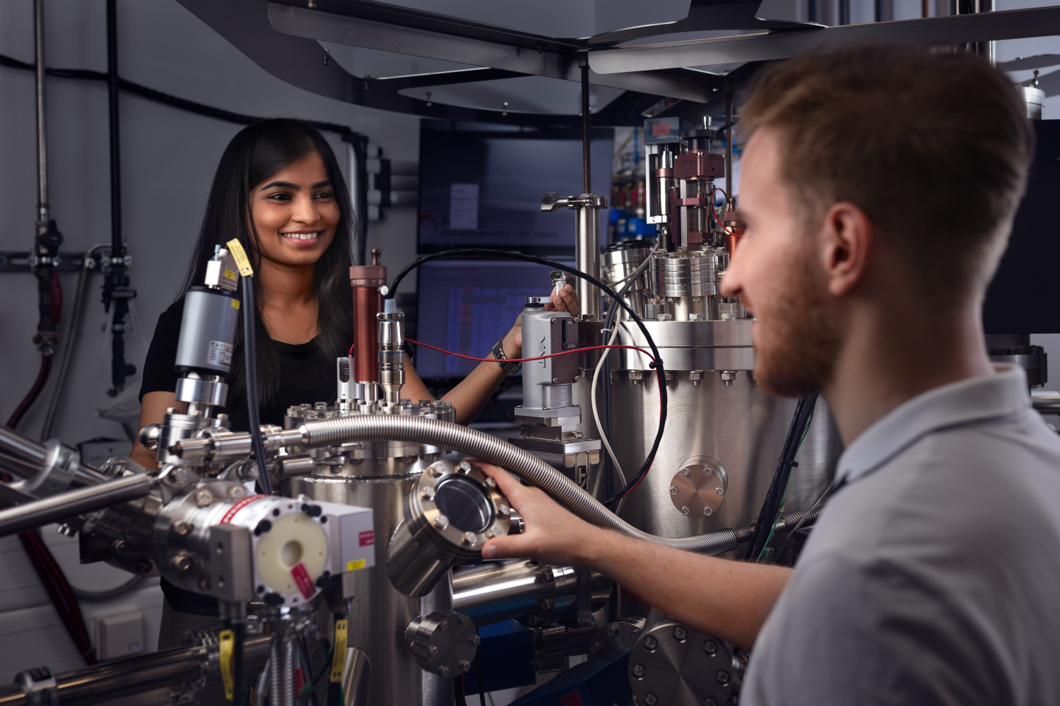 Two people talking over a machine in a lab